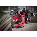 The M18 Random Orbit Sander is a red and black cordless power tool, designed for smoothing surfaces with a compact design.