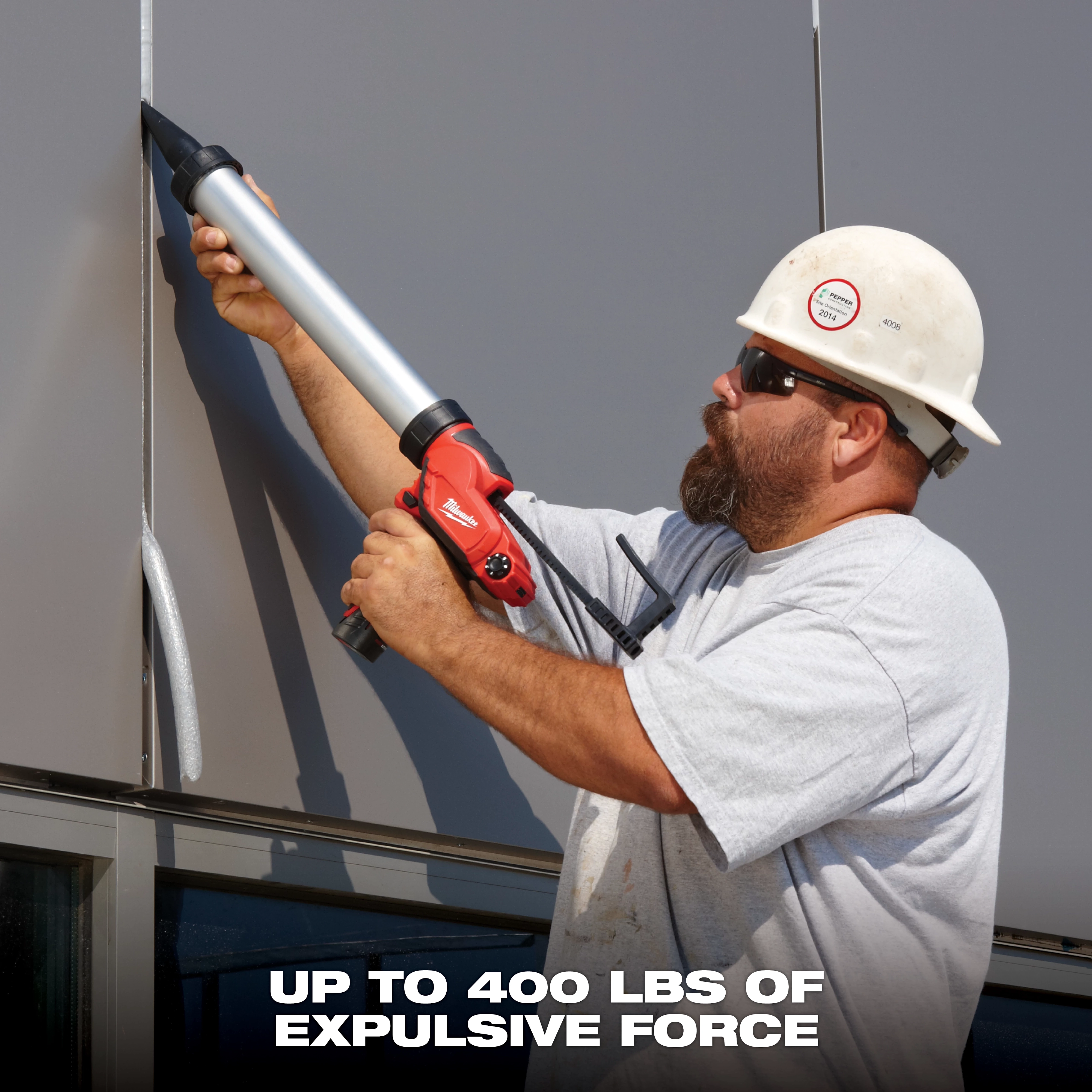 A construction worker uses an M12 12-Volt Lithium-Ion Cordless 10 oz. Caulk and Adhesive Gun (Tool-Only) on a metal panel. The text at the bottom reads "Up to 400 lbs of expulsive force."