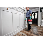 Man using the M12 Handheld Sprayer to spray along wall trim indoors for pest treatment