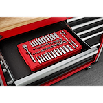 A red tray organizer containing various socket wrenches and accessories is arranged neatly inside an open drawer of a red and black tool chest. The tool chest has multiple drawers and a wooden top surface above the open drawer. The floor beneath is concrete.